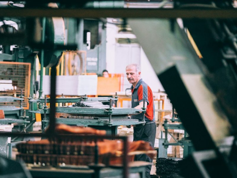 man in orange polo shirt standing in front of table